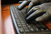 dłonie w czarnych rękawiczkach na klawiaturze komputera